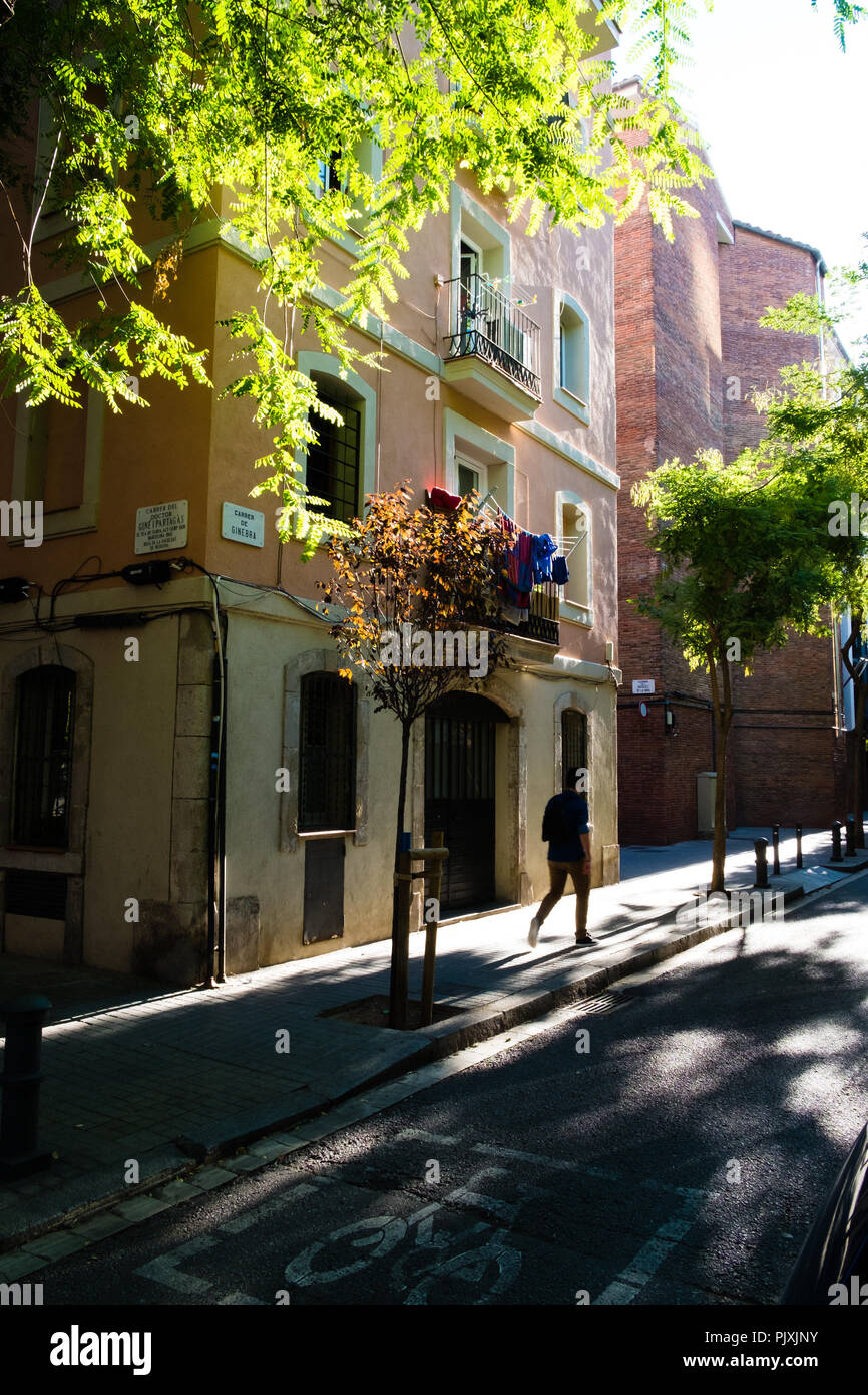 Uomo che cammina lungo una soleggiata strada di Barcellona. Scena tranquilla con ombre di tress. Foto Stock