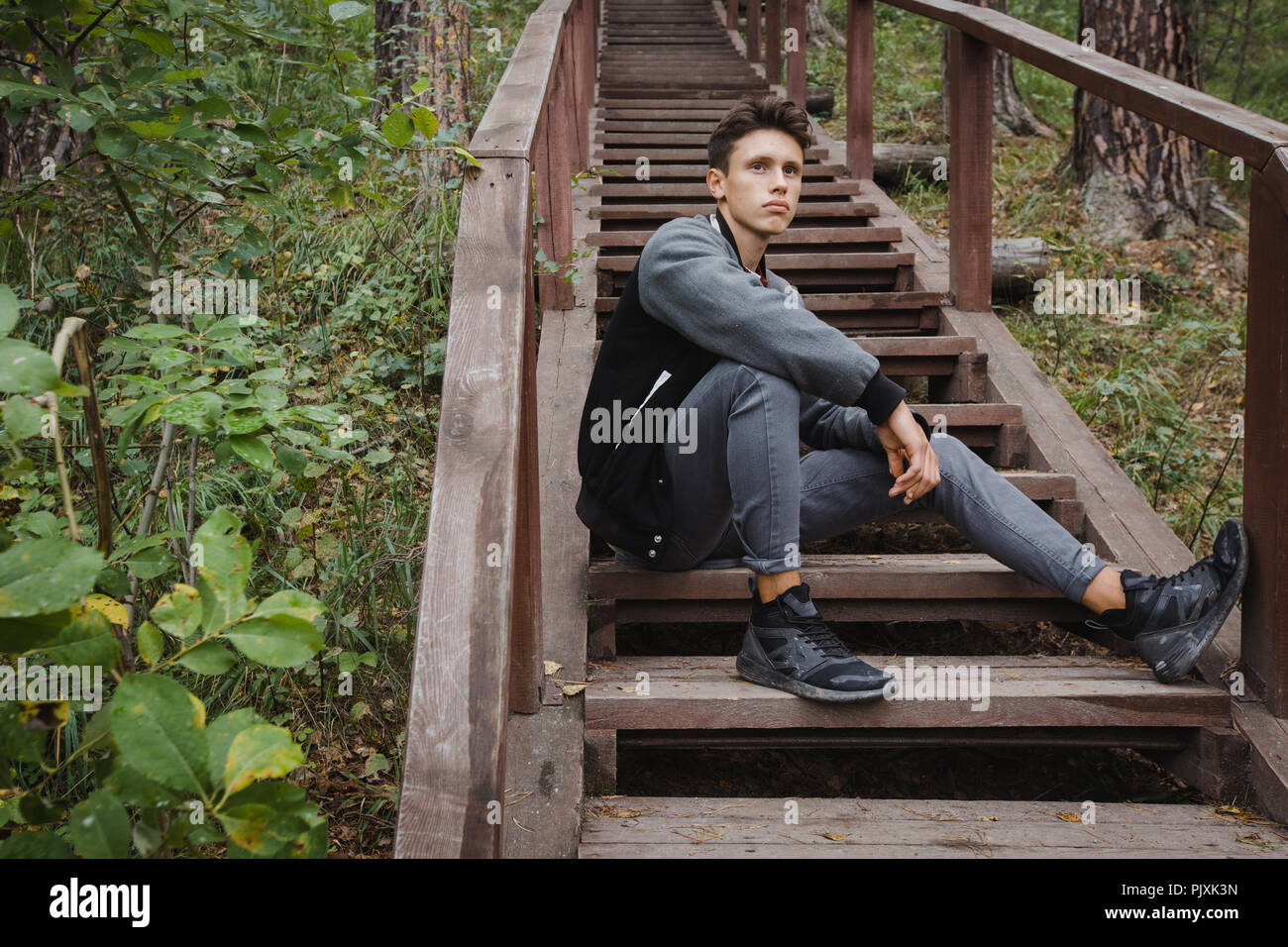 Giovane uomo seduto sulle scale in foresta Foto Stock