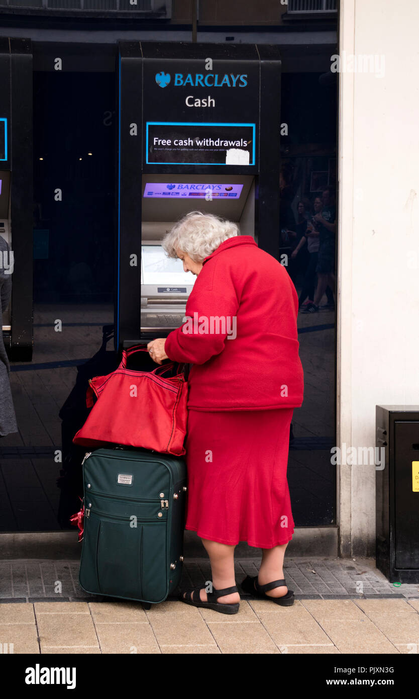 Signora anziana utilizzando un Barclays Bank bancomat, Bristol, Inghilterra, Regno Unito Foto Stock