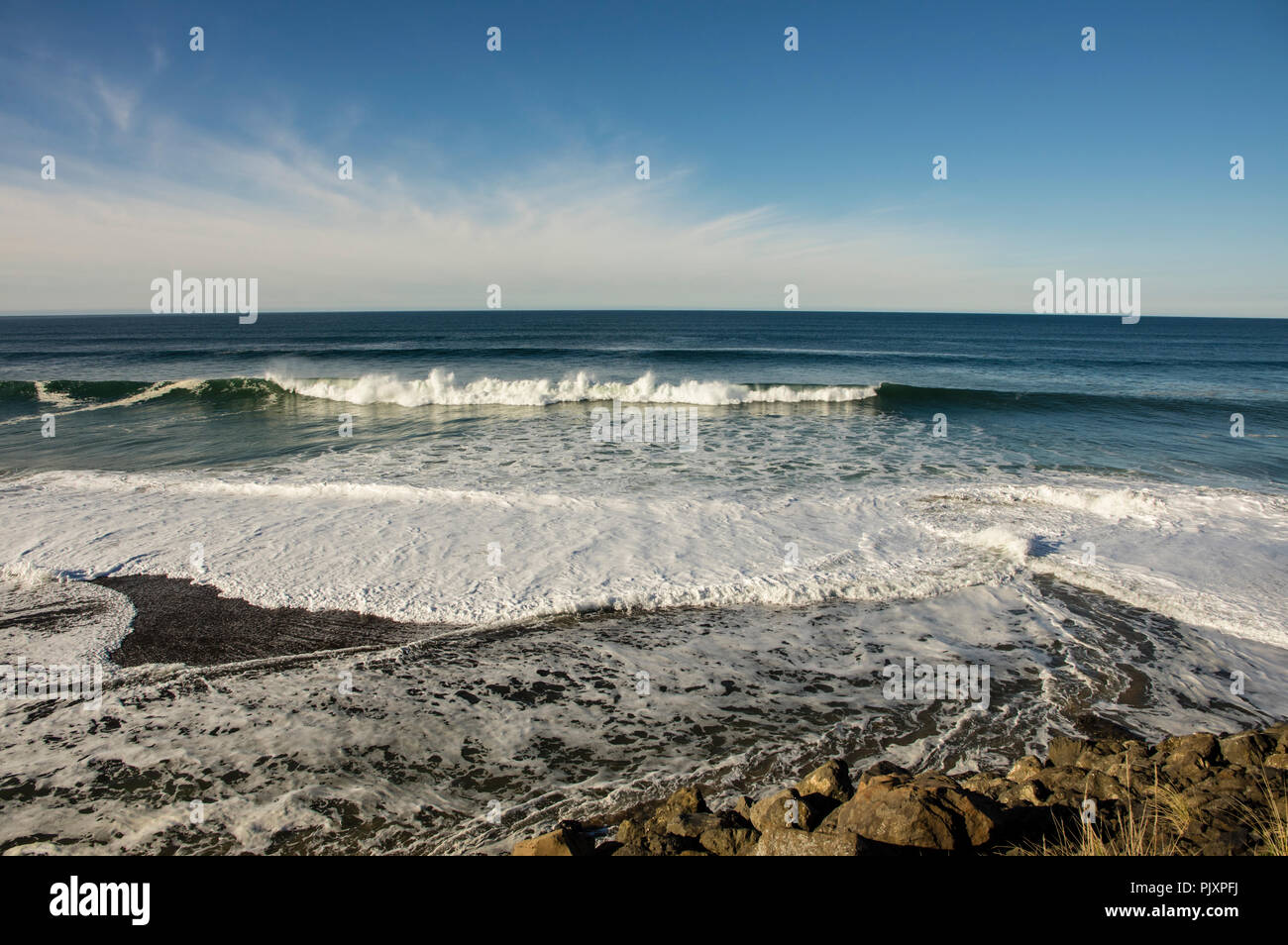 Una vista ovest per una calma Oceano Pacifico con il blu del cielo e pianeggiante e nuvole Foto Stock