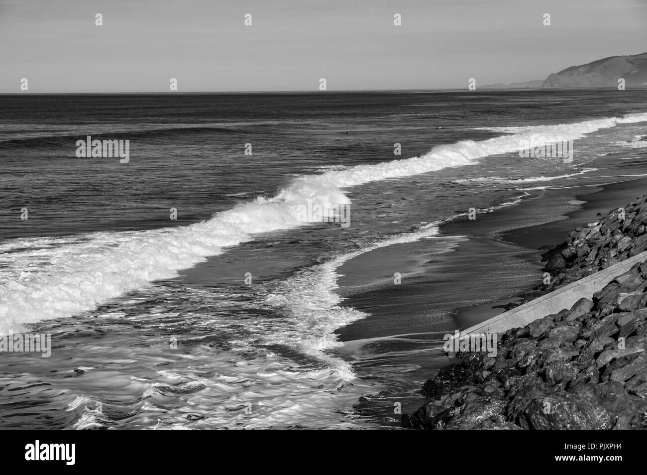 Surfers per tentare la fortuna su una spiaggia tranquilla con il minimo di surf Foto Stock