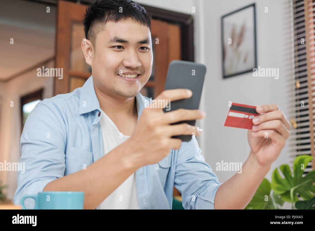 Uomo asiatico shopping on line con carta di credito e il telefono cellulare a casa.uno stile di vita digitale con la tecnologia Foto Stock