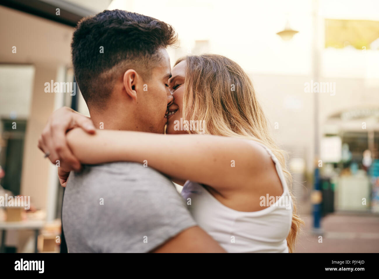 Affettuosa coppia giovane condividendo un bacio mentre godendo un momento romantico insieme nella città Foto Stock