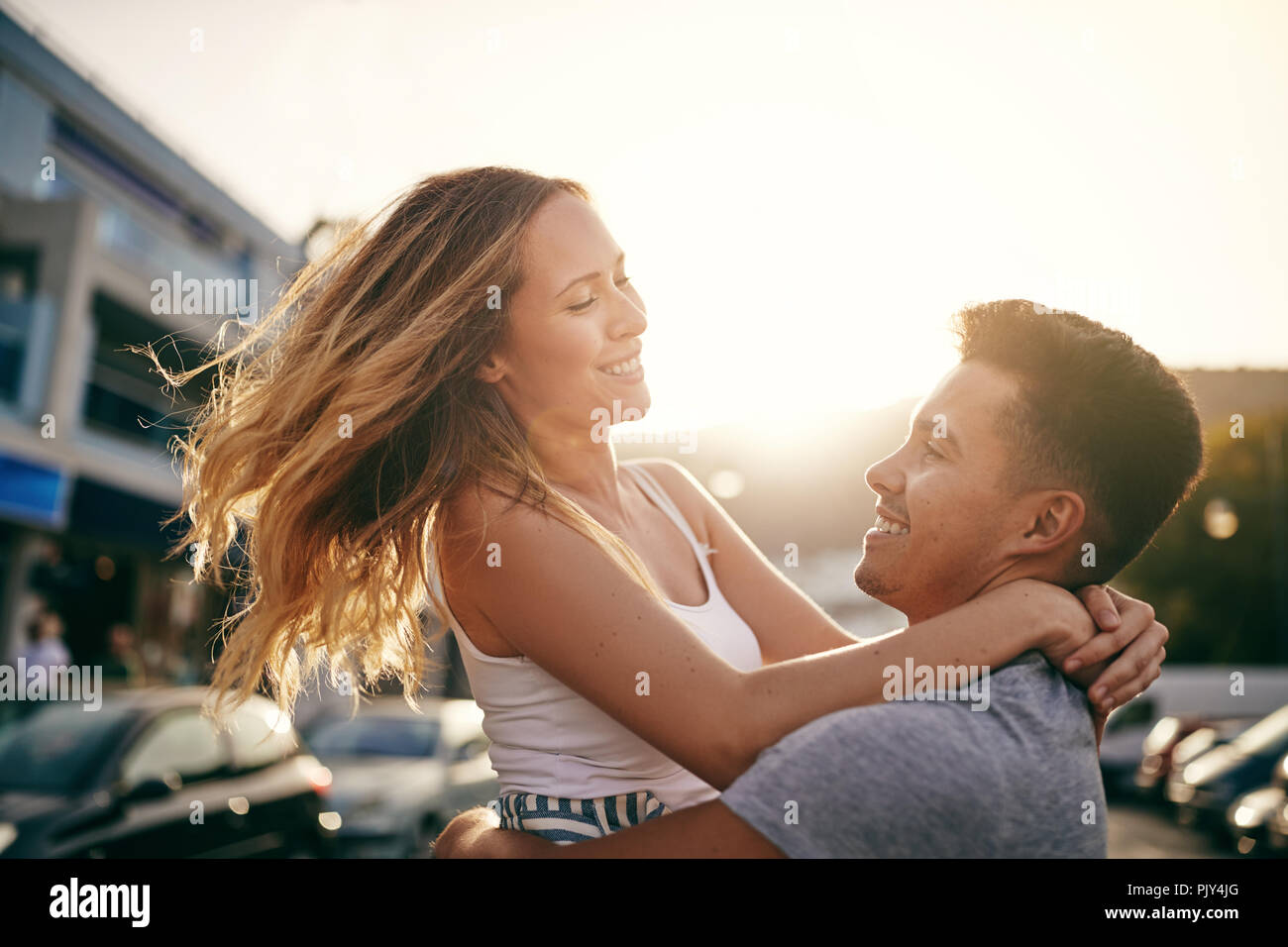 Sorridente giovane uomo fa roteare la sua ragazza ridere nelle sue braccia pur avendo una giornata di divertimento insieme in città Foto Stock