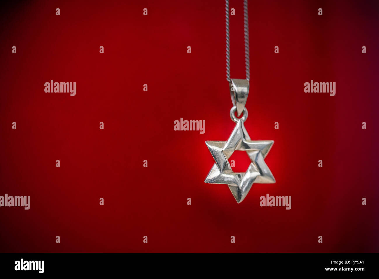 Collana in argento con una stella d'argento di Davide, pendente contro lo sfondo di colore rosso - il giudaismo concept Foto Stock