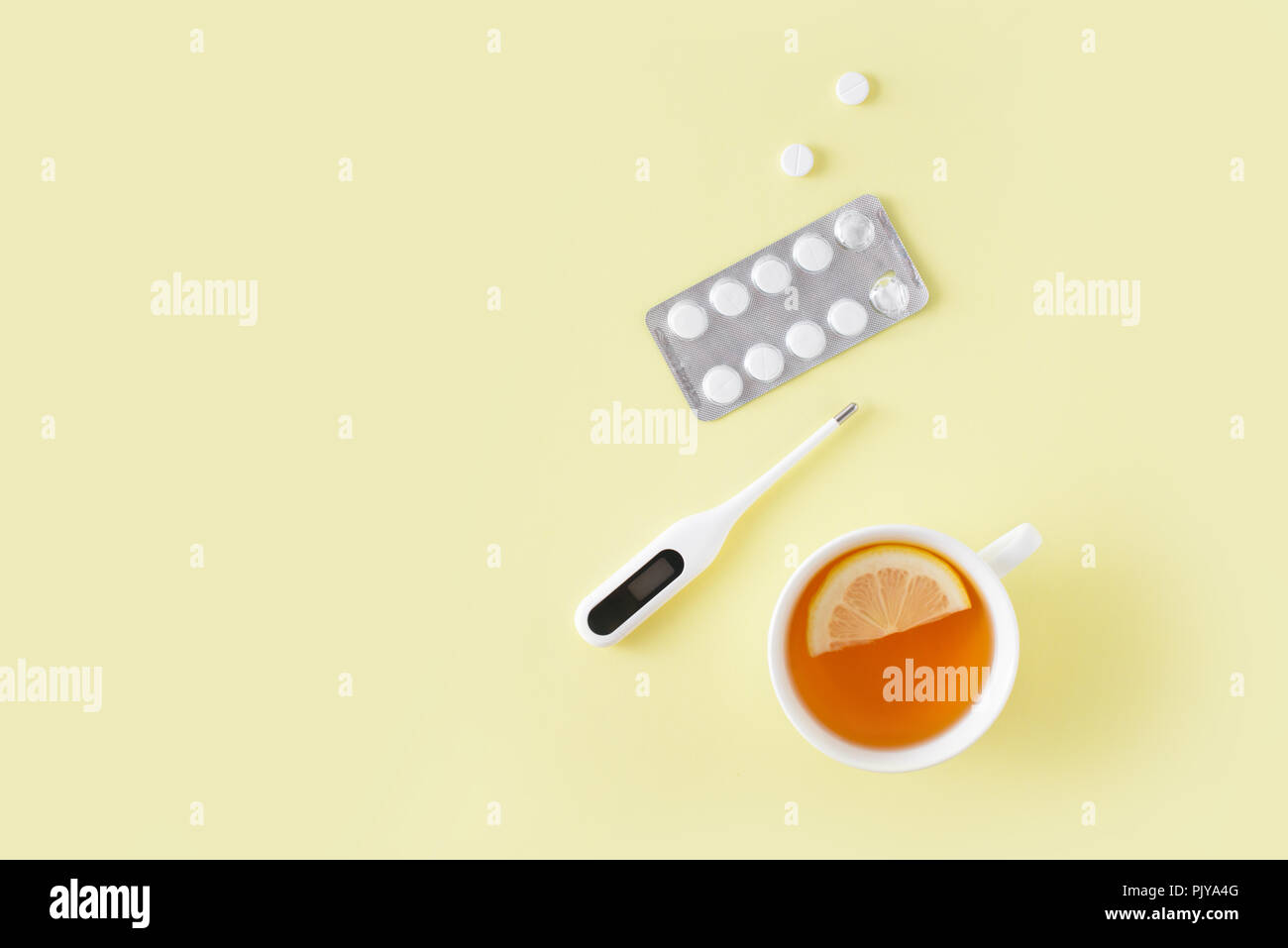Pillole, termometro e tazza di tè su sfondo giallo. Raffreddore e influenza il trattamento impostato. Appartamento laico, vista dall'alto. Copia gratuita dello spazio. Foto Stock