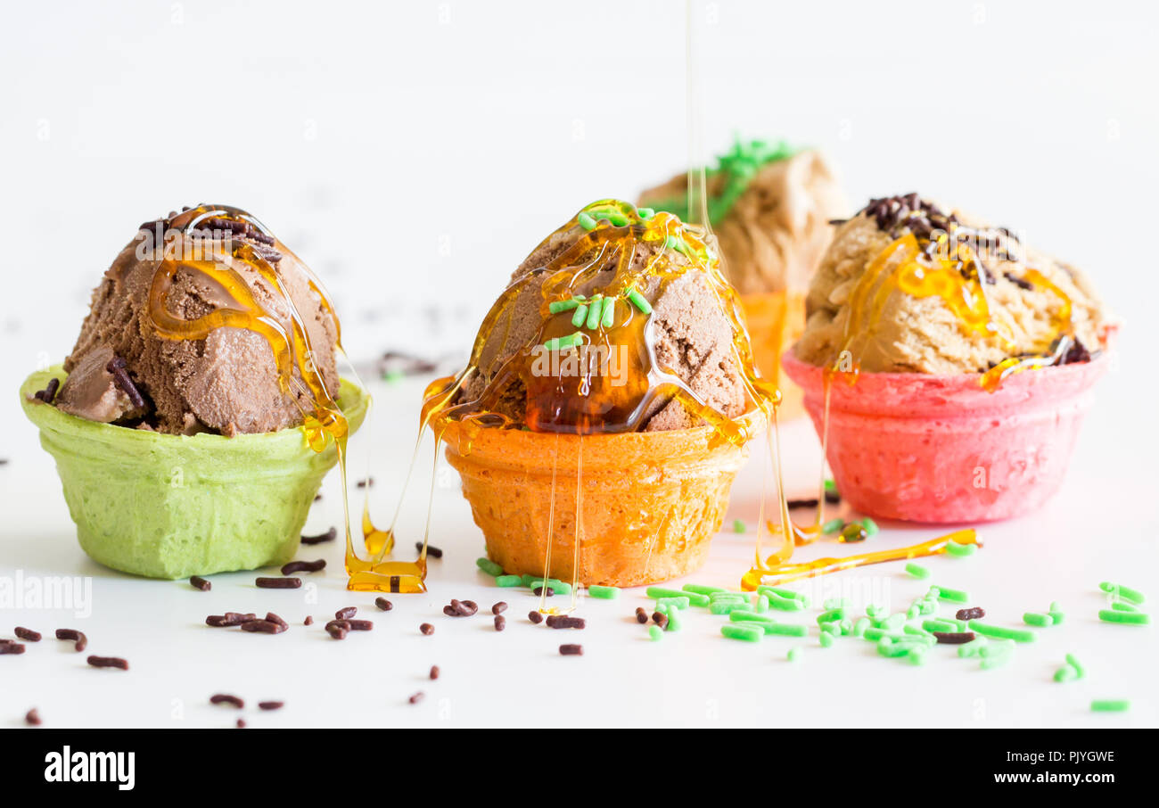 Piccolo disordine coppe di gelato con un pizzico di sciroppo e spruzzata su sfondo bianco - bambino compleanno divertente coni gelato Foto Stock