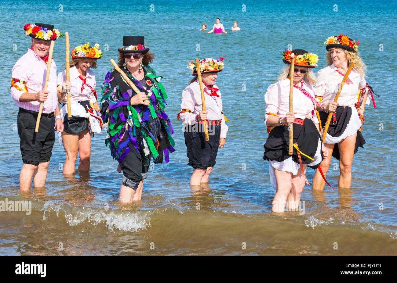 Swanage, Dorset, Regno Unito. Il 9 settembre 2018. La folla gregge al 2° giorno di Swanage Folk Festival per vedere i gruppi di danza e musica lungo il lungomare. Delizioso caldo clima soleggiato sedotto alcuni ballerini di danza in mare al termine di un weekend meraviglioso. Morris ballerini, membri di Phoenix Morris dancing in mare con gli stati del paletto di confine di covata Morris. Credito: Carolyn Jenkins/Alamy Live News Foto Stock