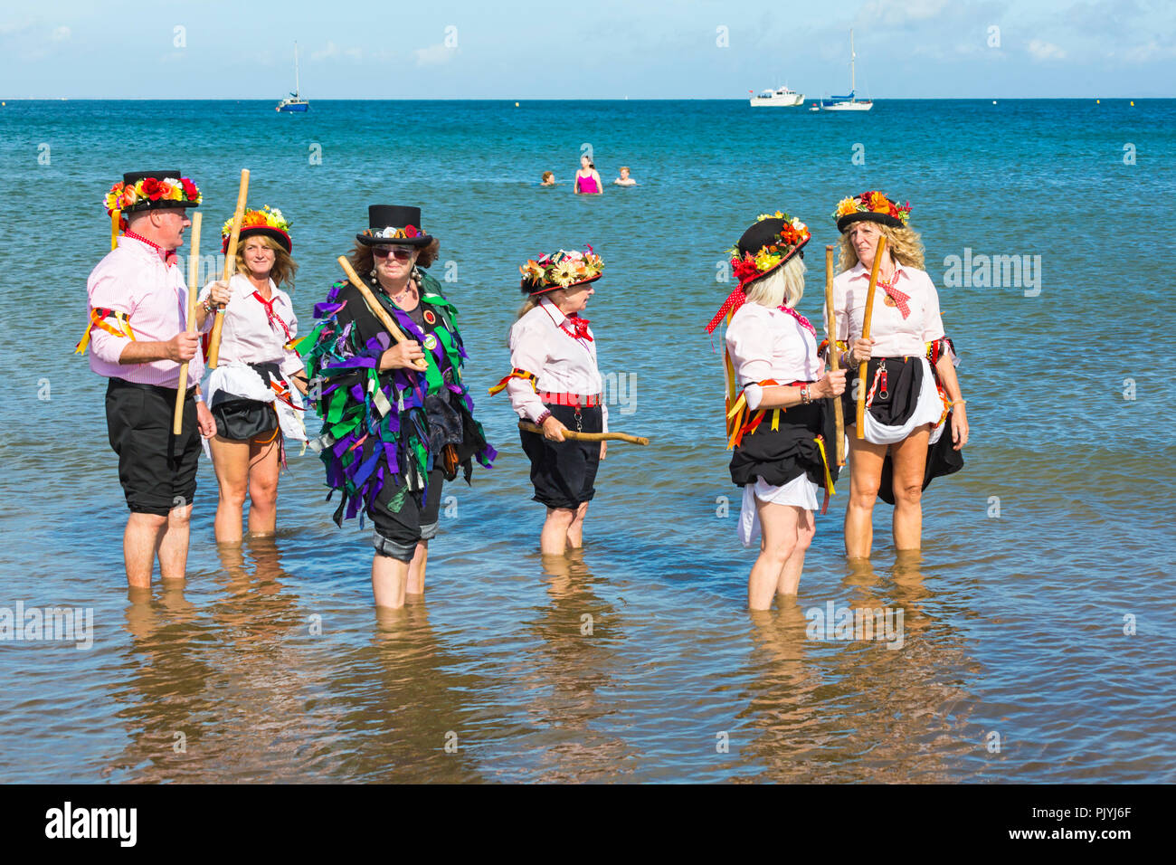 Swanage, Dorset, Regno Unito. Il 9 settembre 2018. La folla gregge al 2° giorno di Swanage Folk Festival per vedere i gruppi di danza e musica lungo il lungomare. Delizioso caldo clima soleggiato sedotto alcuni ballerini di danza in mare al termine di un weekend meraviglioso. Morris ballerini, membri di Phoenix Morris dancing in mare con gli stati del paletto di confine di covata Morris. Credito: Carolyn Jenkins/Alamy Live News Foto Stock