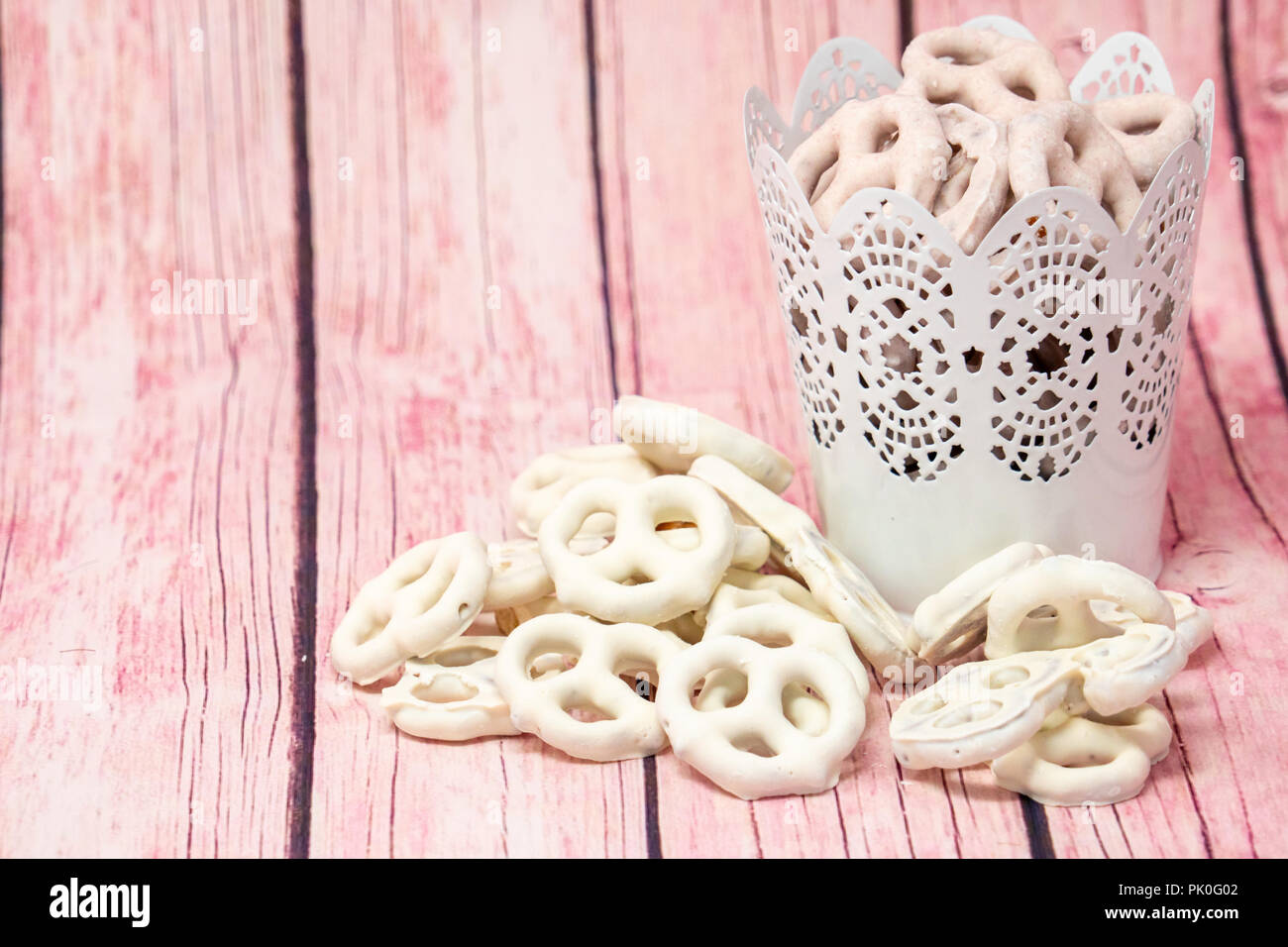 Bella yogurt deliziosi salatini coperto di vaniglia e lampone sapori. Alcuni in un secchio. Rosa sullo sfondo di legno Foto Stock