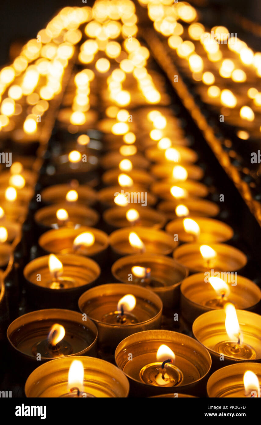 Molte belle candele accese in una fila incandescente con un colore giallo  dorato - luce messa a fuoco selettiva Foto stock - Alamy