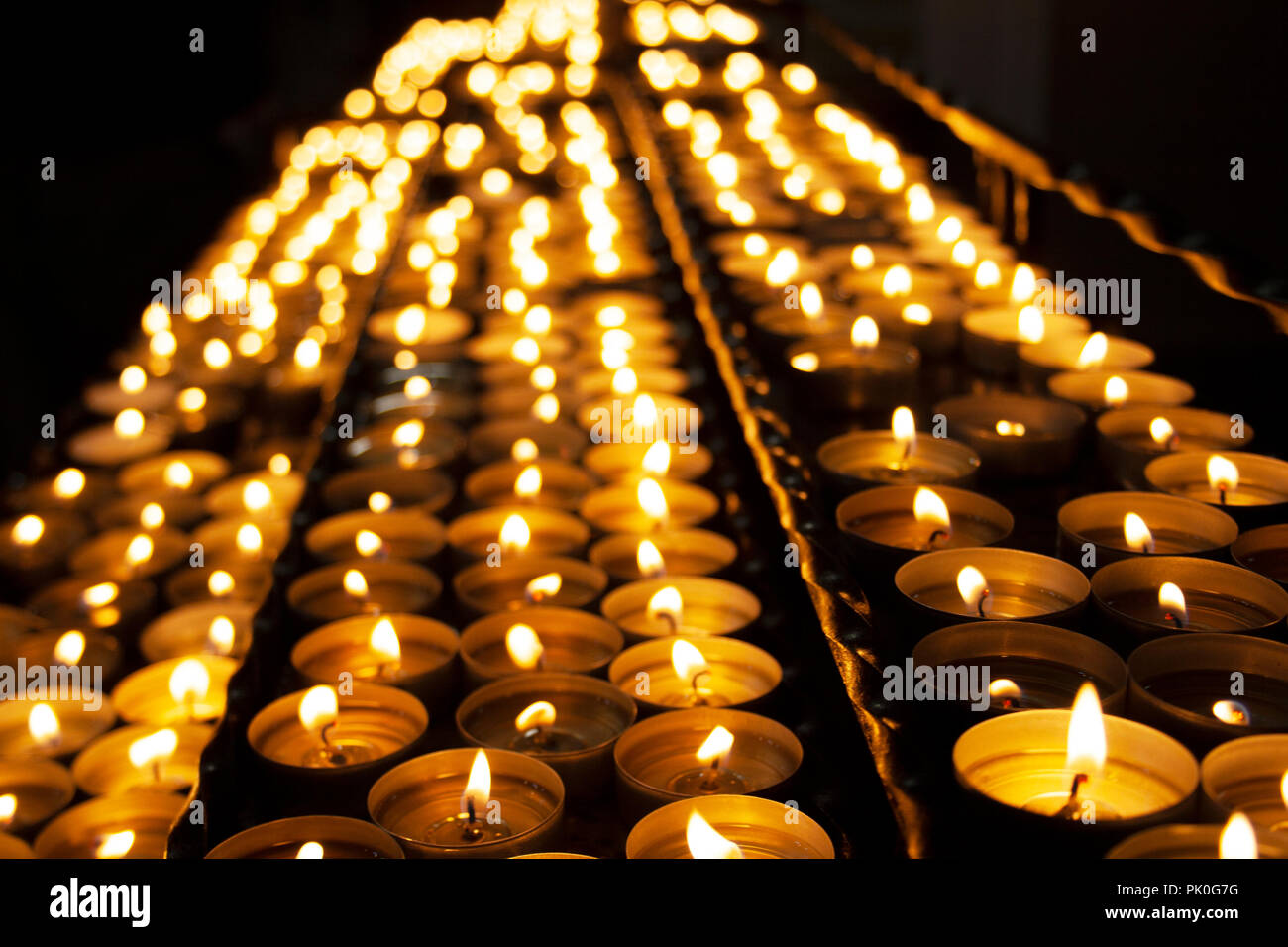 Molte belle candele accese in una fila incandescente con un colore giallo dorato - luce messa a fuoco selettiva Foto Stock