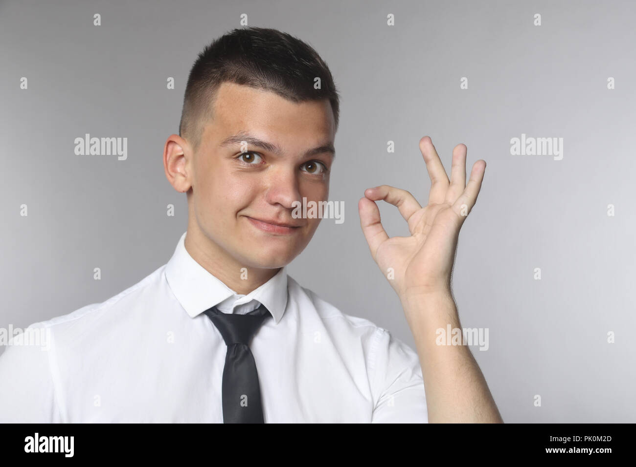 Felice Giovane Uomo in camicia e cravatta gesti segno OK e sorridente Foto Stock