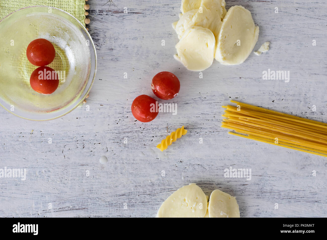 Sfondo alimentare/ pomodoro ciliegino, spaghetti, la Mozzarella a sfere di luce sullo sfondo di legno/ immagine concettuale del coperchio di cottura Foto Stock