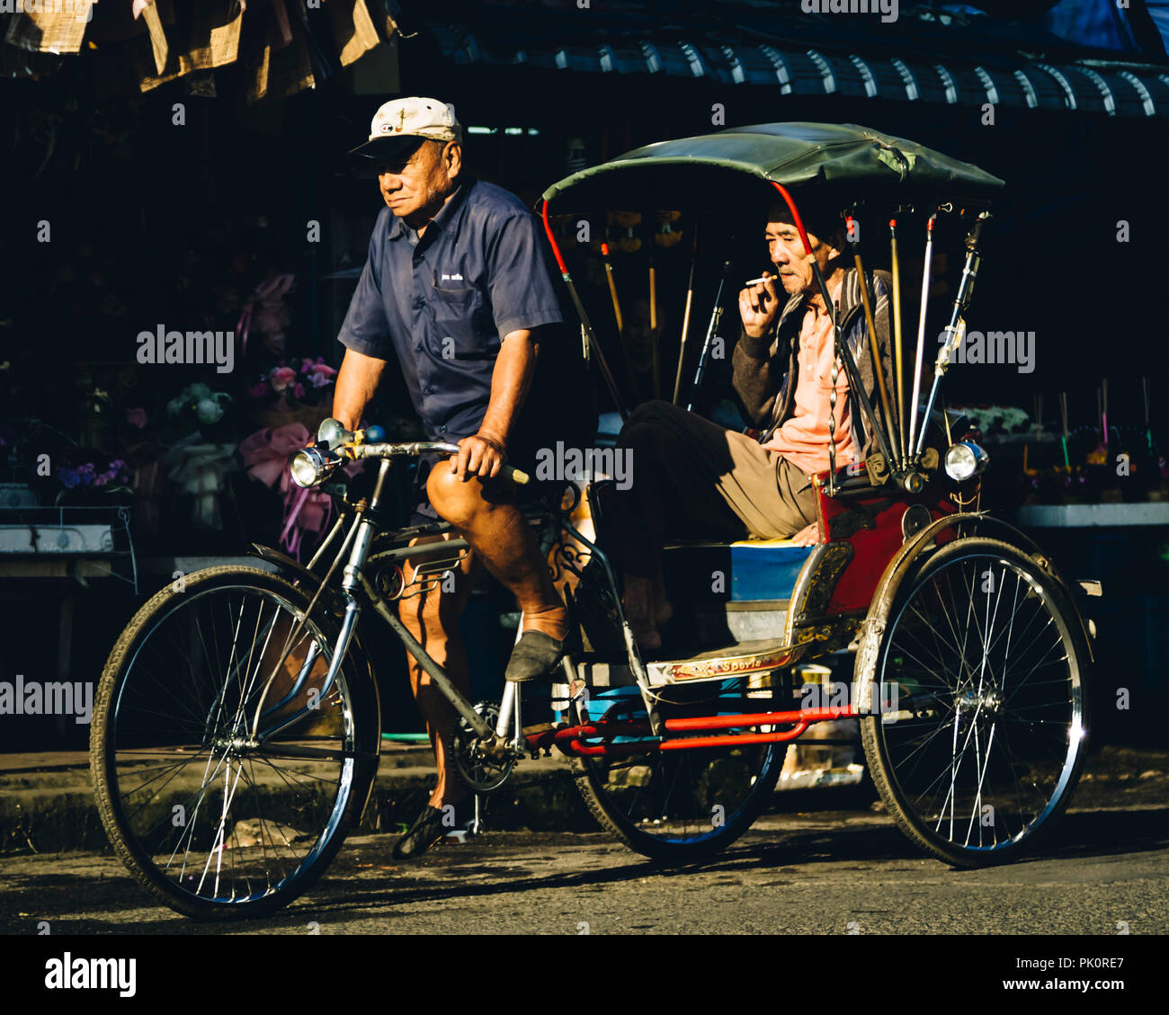 Uomo cinese di fumare una sigaretta su un rickshaw in Chiang Mai Thailandia Foto Stock