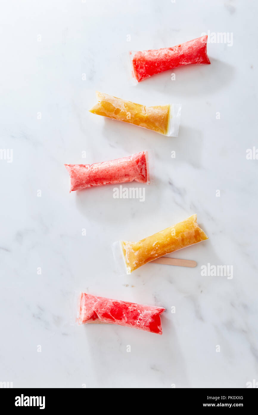Caramelle di ghiaccio di sacchetti di plastica su sfondo marmo. Perfetto per i dolci fatti in casa pop di congelatore. Sana dessert estivo Foto Stock
