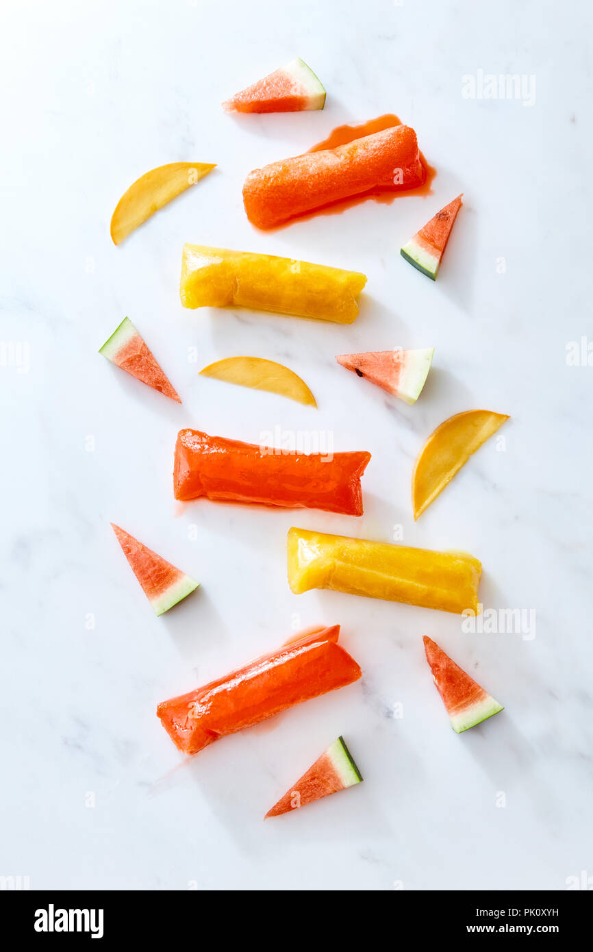 Freeze ice pop tubo in plastica per il confezionamento di ghiaccioli con fetta di anguria e pesca su sfondo marmo, vista dall'alto. Sana dessert estivo Foto Stock