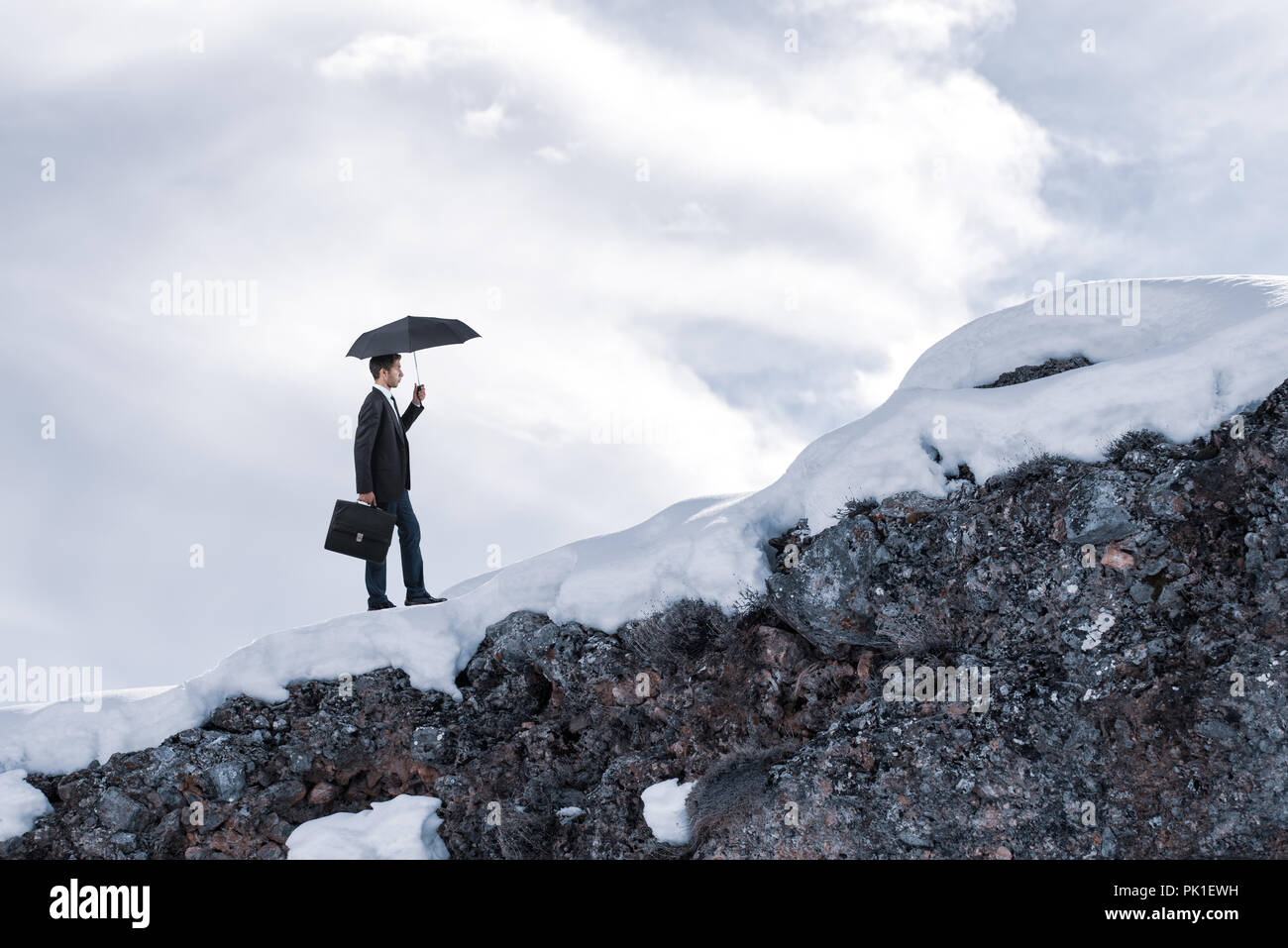 Imprenditore a piedi con ombrellone e mantenendo la sua azienda. Foto Stock