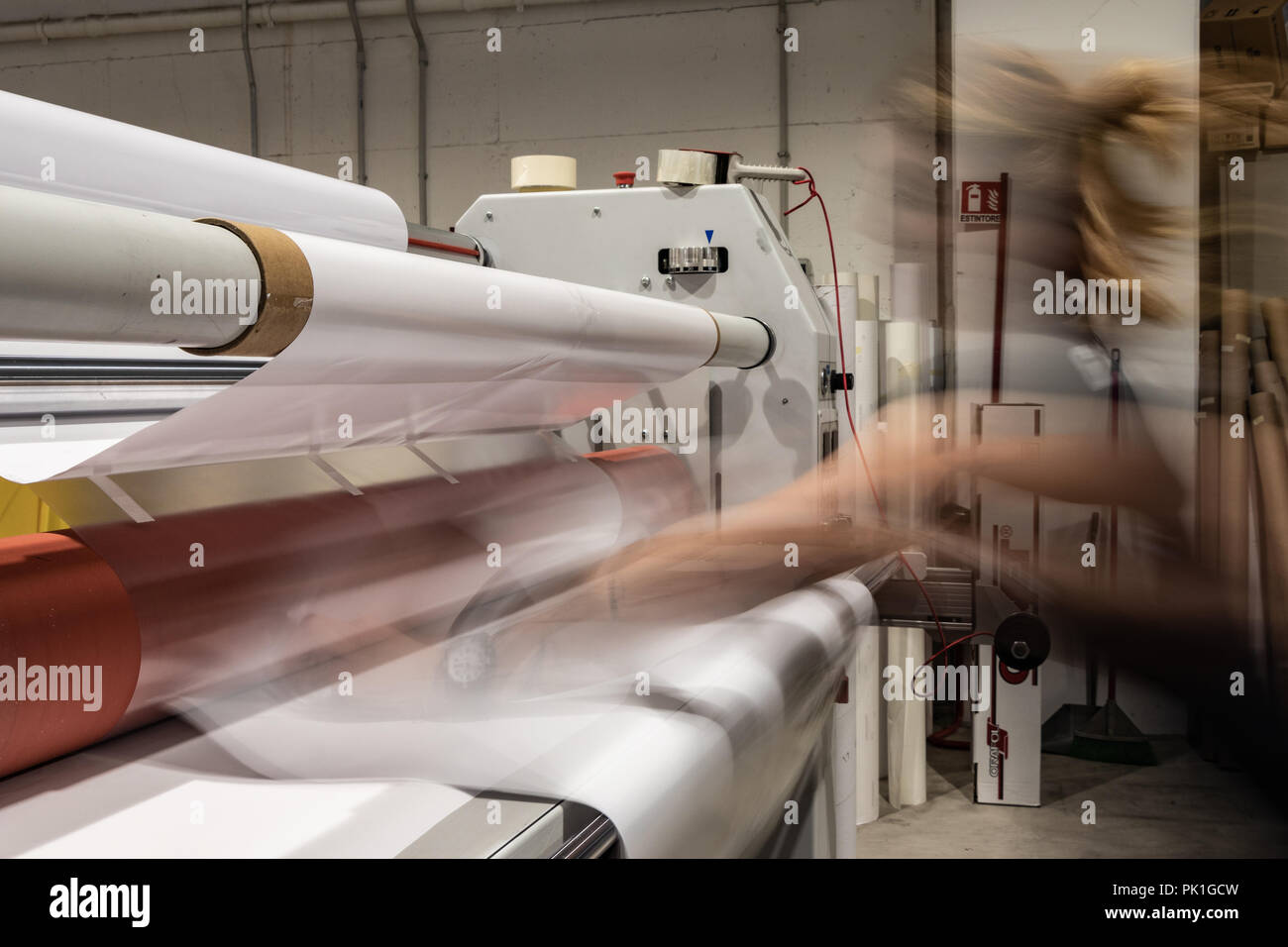 Grande stampa professionale laminatore, armati con rossi grandi rotoli di carta lucida e piccoli tubi di pellicola trasparente. Foto Stock