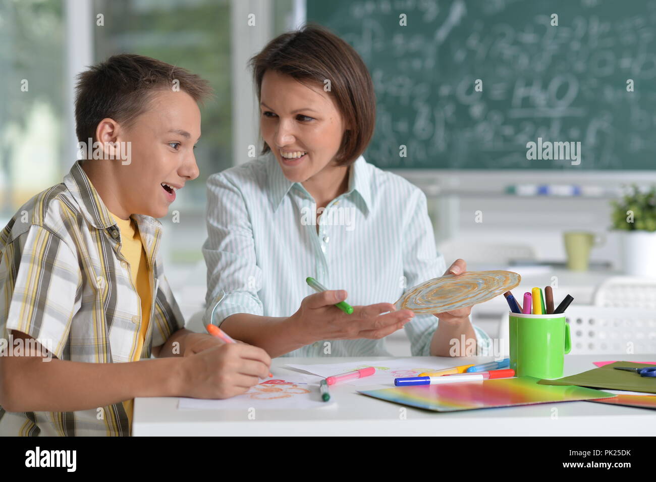 Ritratto di scolaro e maestro seduta in aula Foto Stock