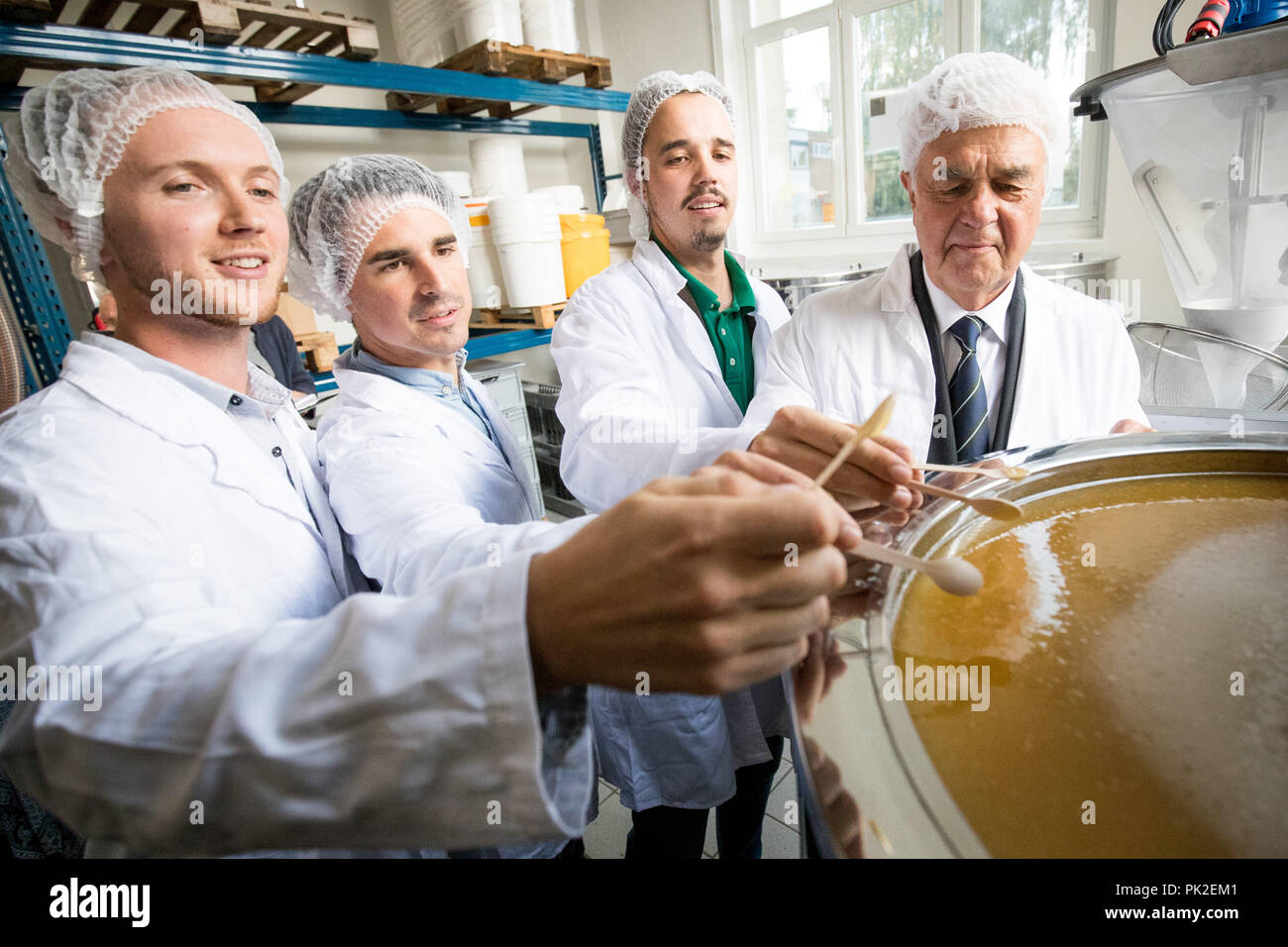 Amburgo, Germania. Decimo Sep, 2018. 10.09.2018, Amburgo: Frank Horch (partito-inferiore, r), il senatore per l'economia, dei trasporti e dell'innovazione in Amburgo, fondatore e amministratore delegato dell'azienda start-up 'BEEsharing' Otmar Trenk (secondo da destra) e il suo co-fondatori Nils Gerber (l) e Wolfgang Reuter provare città fresca miele nell'imbottigliamento dell'azienda. Il core business di start-up è professionale Servizi di impollinazione attraverso la mediazione delle colonie attraverso una piattaforma online. Credito: Christian Charisius/dpa/Alamy Live News Foto Stock