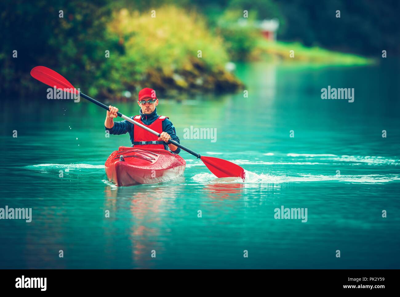 Il lago glaciale di viaggio in kayak. Turismo caucasica Paddling in Red Kayak. Foto Stock