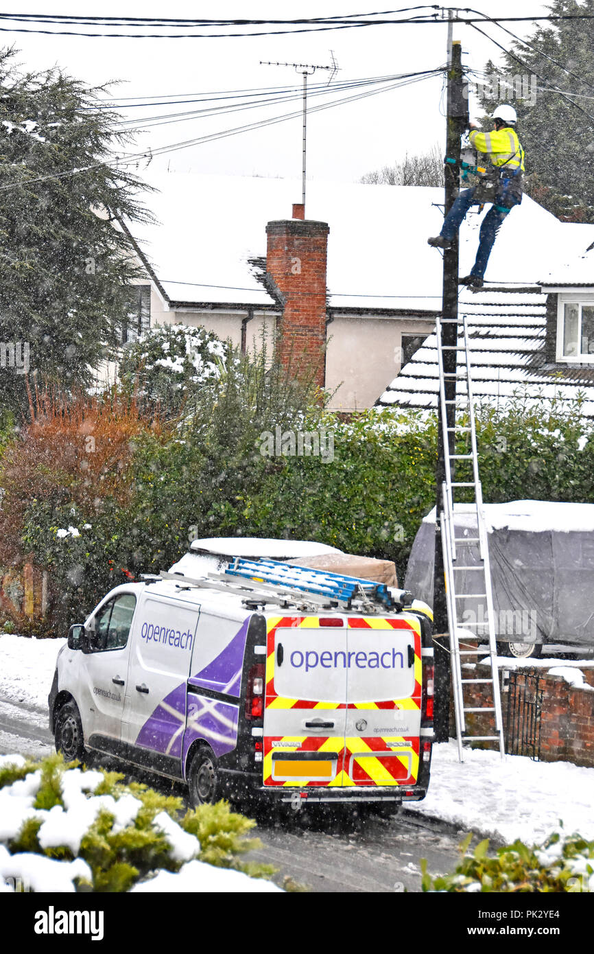 Neve invernale street scene BT openreach van & ingegnere bianco uomo elmetto alta vis giacca scaletta lavorando sulla riparazione home linee telefoniche England Regno Unito Foto Stock