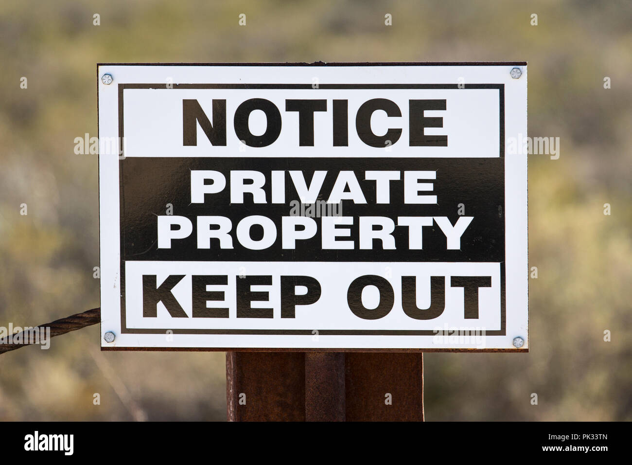 Weathered generica proprietà privata tenere fuori segno sul metallo arrugginito palo da recinzione. Foto Stock