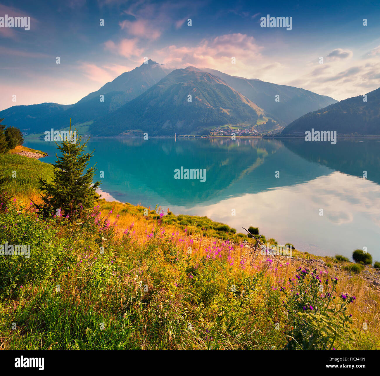 Colorata estate mattina nella Resia (Reschensee) lago. Curon Venosta villaggio della nebbia di mattina. Alpi, l'Italia, l'Europa. Foto Stock
