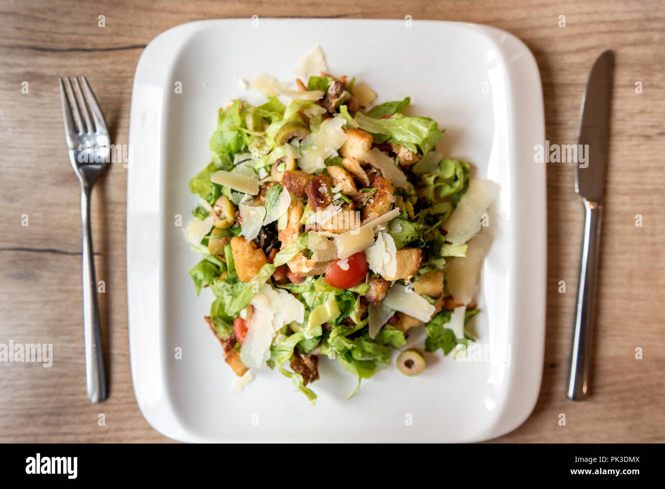 Piatto di insalata caesar con utensili sul ristorante tavolo in legno Foto Stock