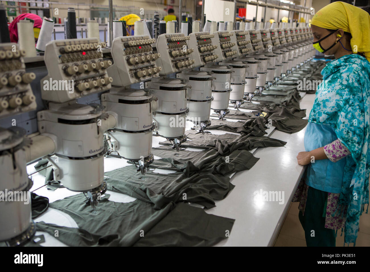 Indumento dei lavoratori durante il lavoro su macchine da cucire all'interno di una fabbrica di indumento in Bangladesh. Foto Stock