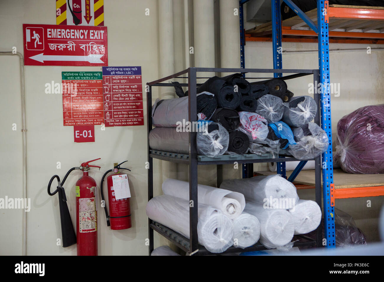 Estintori e uscita di emergenza segno dentro una fabbrica di indumento in Bangladesh. Foto Stock