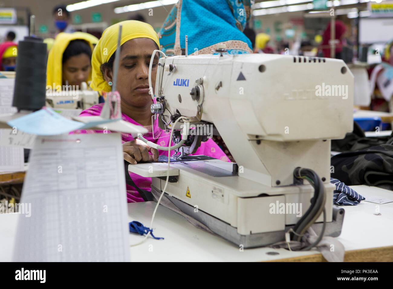 Un indumento lavoratore a lavorare su una macchina da cucire all'interno di una fabbrica di indumento in Bangladesh. Foto Stock