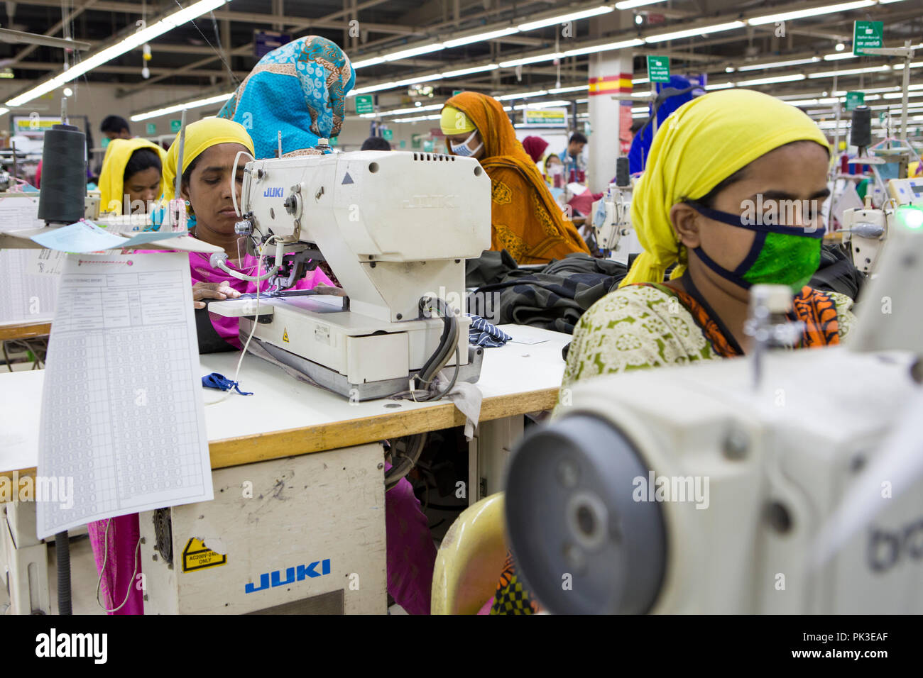 Un indumento lavoratore a lavorare su una macchina da cucire all'interno di una fabbrica di indumento in Bangladesh. Foto Stock