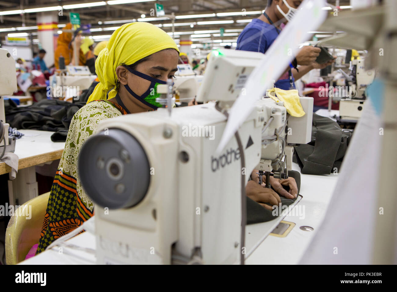 Un indumento lavoratore a lavorare su una macchina da cucire all'interno di una fabbrica di indumento in Bangladesh. Foto Stock