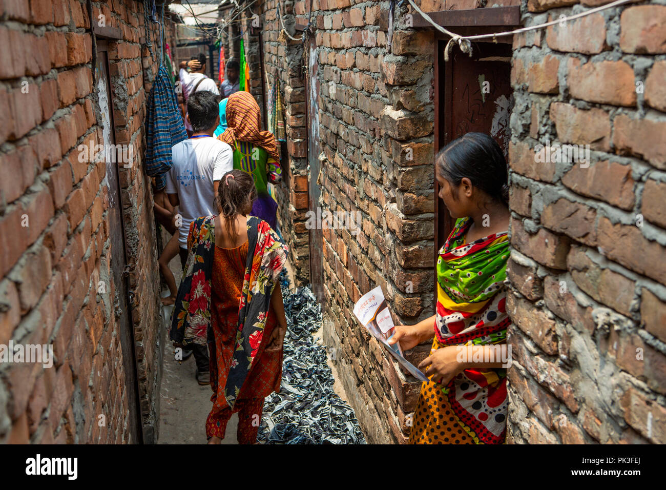 Comunità personale di campo fuori a parlare ai lavoratori di indumento nelle baraccopoli dove vivono a Dhaka, nel Bangladesh. Foto Stock