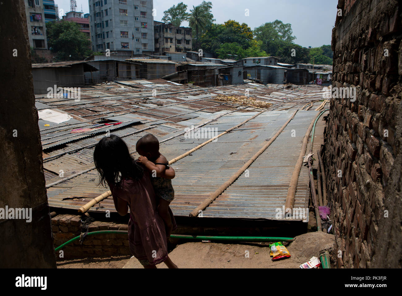 Una ragazza porta un bambino giù per le scale di una delle baraccopoli di Dacca in Bangladesh. Foto Stock