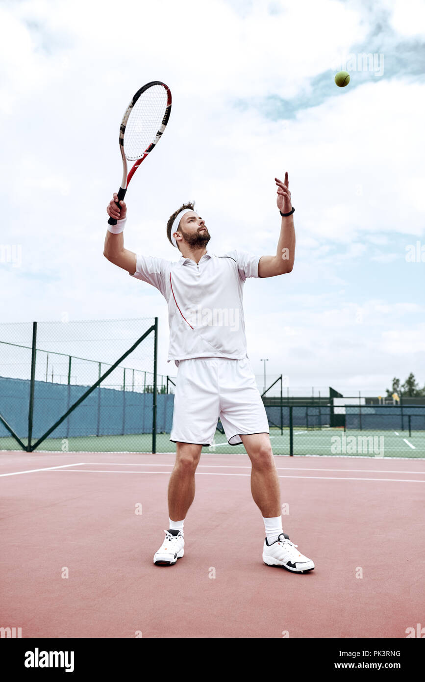 Giocatore di tennis professionista sta facendo un calcio tennis su un campo da tennis su una soleggiata mattina d'estate. Il vestito in abbigliamento sportivo. Foto Stock