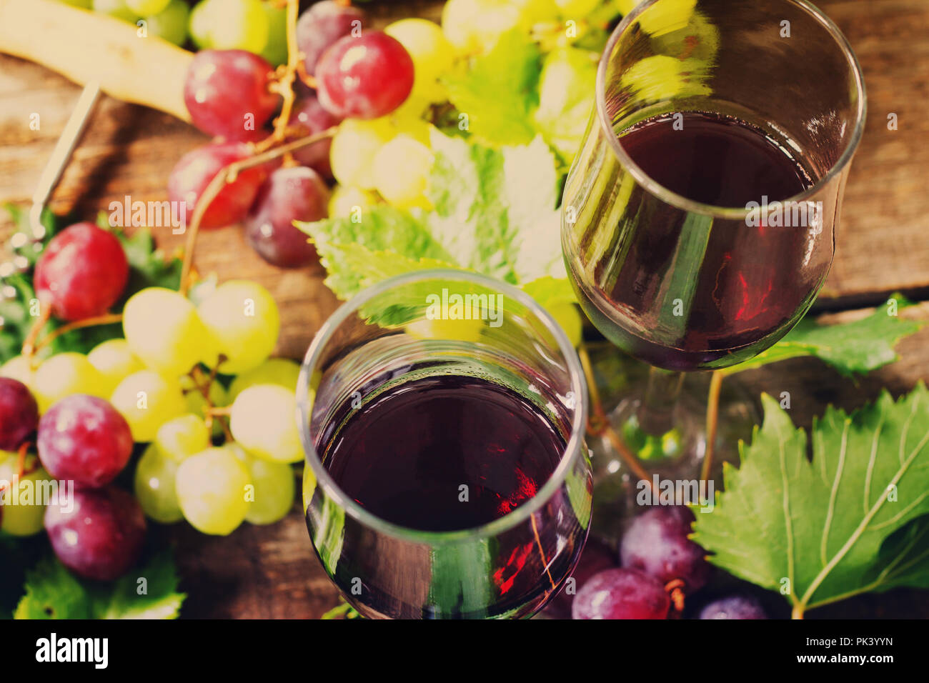 Sfondo del vino. Vino rosso in bicchieri, bottiglia, uve su sfondo vintage, il concetto di vino. Foto Stock