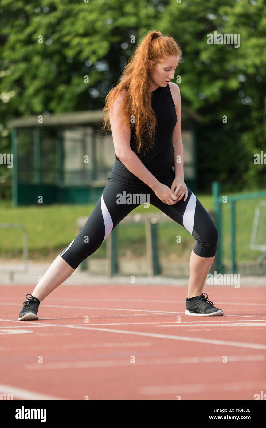 Atletica femmina esercita sulla via di corsa Foto Stock