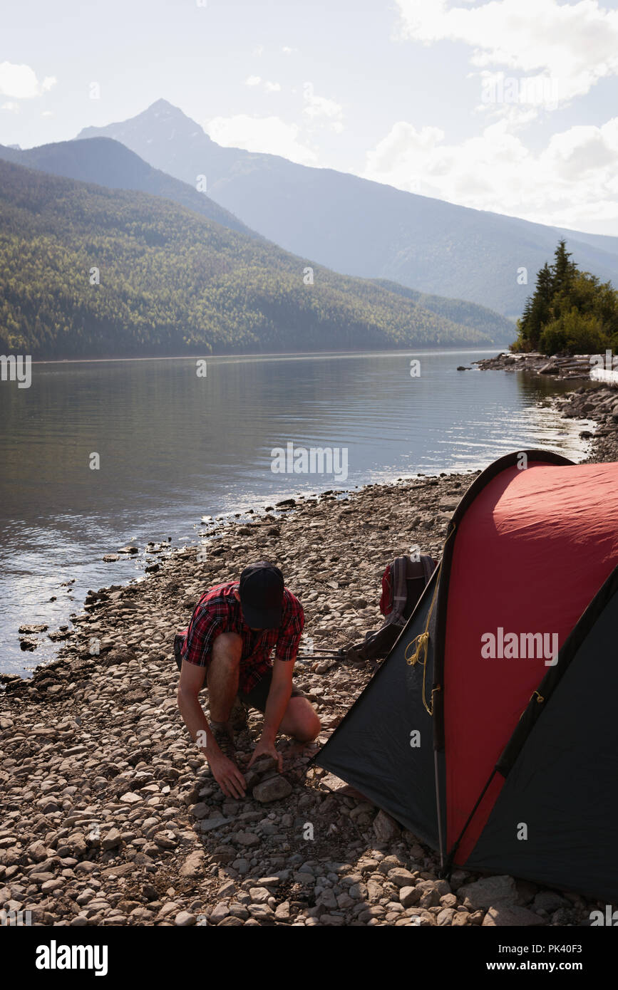 L'uomo impostazione tenda vicino riverside Foto Stock