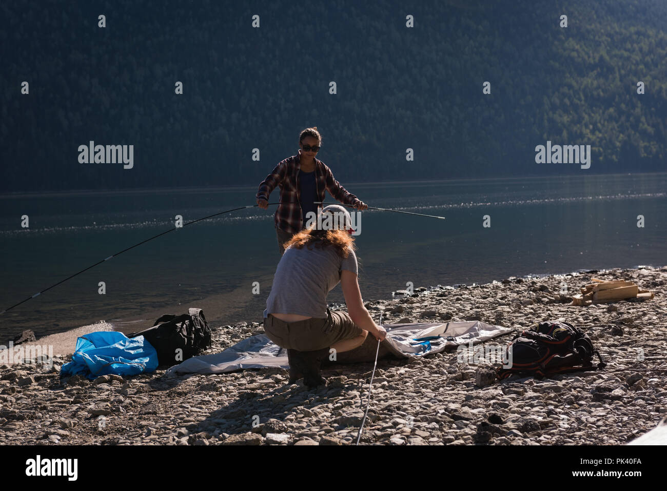 Giovane impostazione tenda vicino riverside Foto Stock