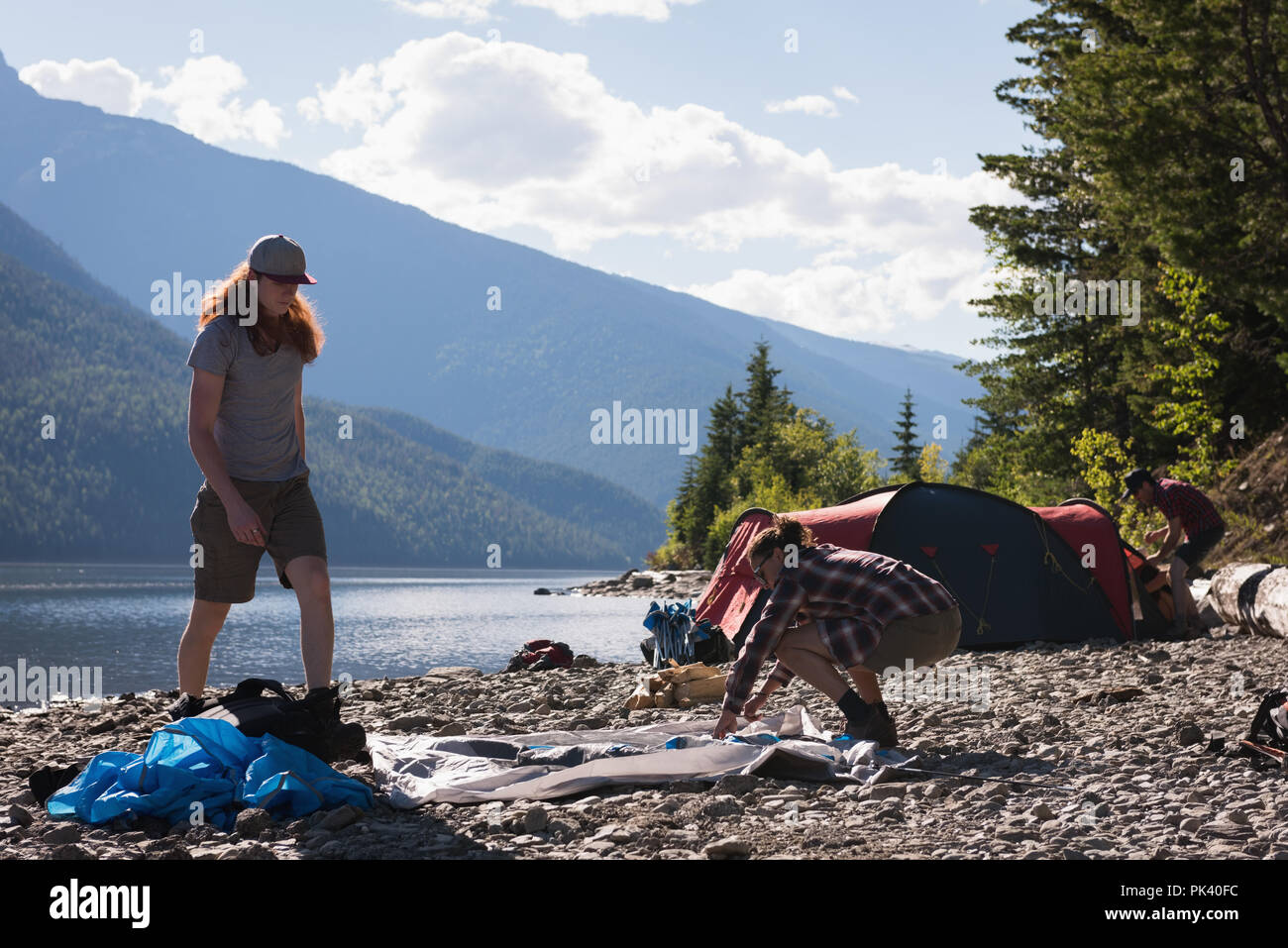 Giovane impostazione tenda vicino riverside Foto Stock
