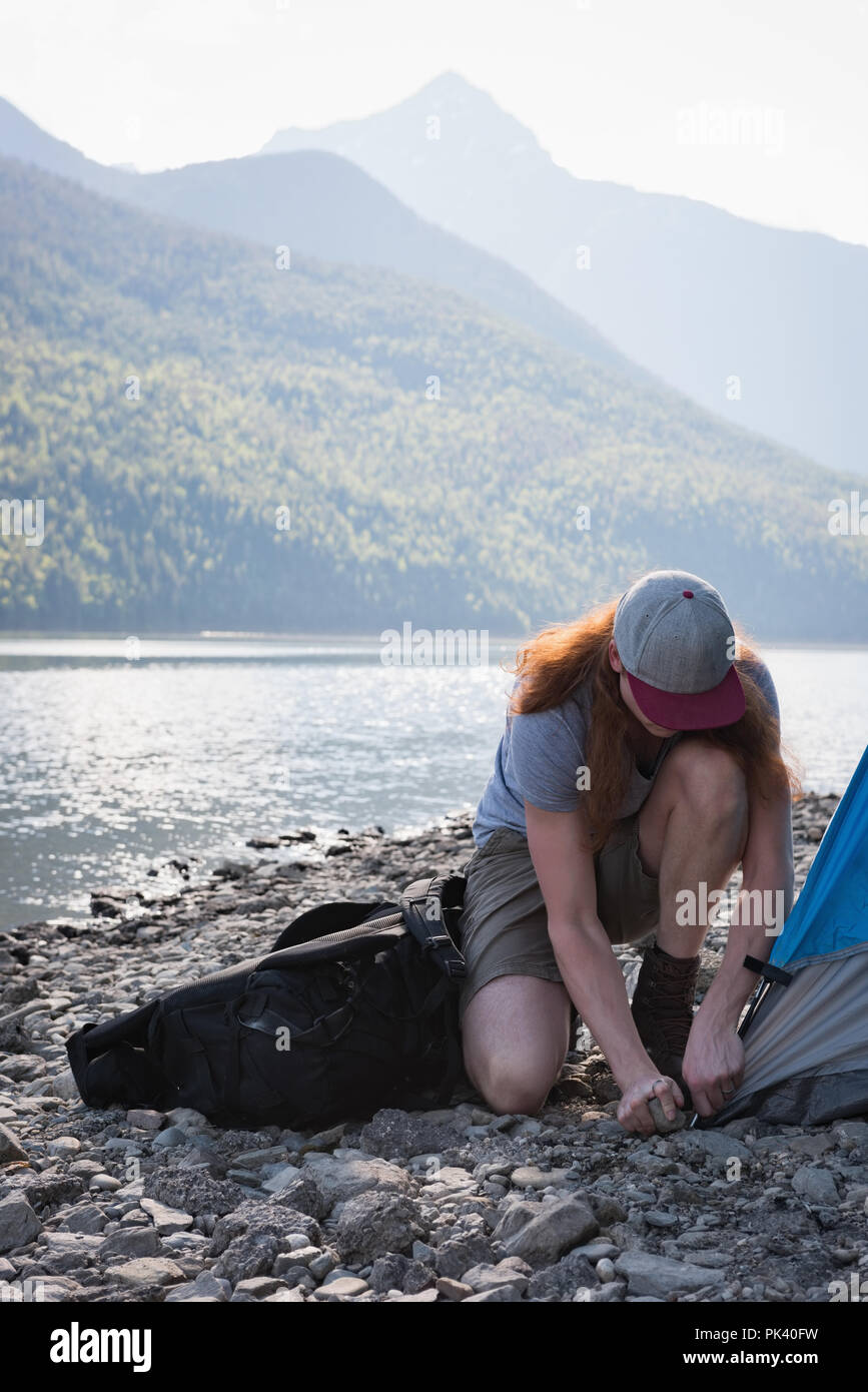 Donna impostazione tenda vicino riverside Foto Stock