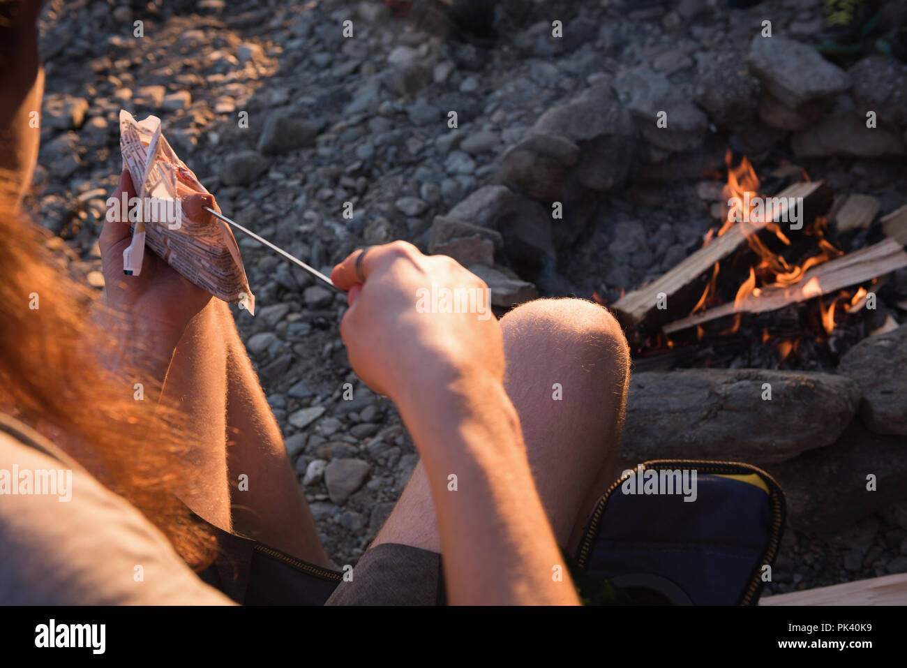 Donna riscaldamento hot dog vicino al fuoco Foto Stock