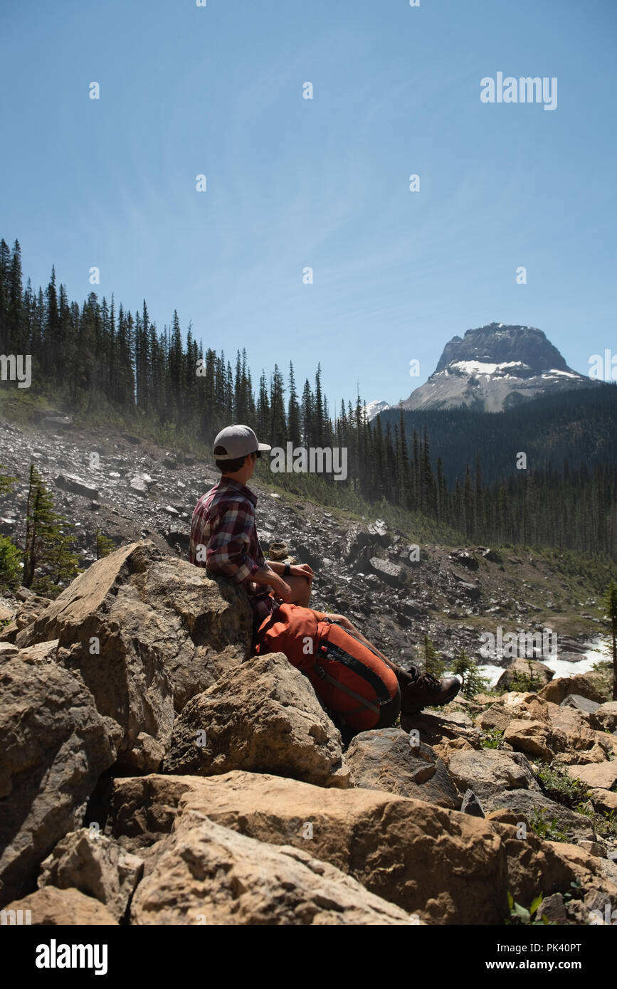 Escursionista maschile seduto su di una roccia alla campagna Foto Stock