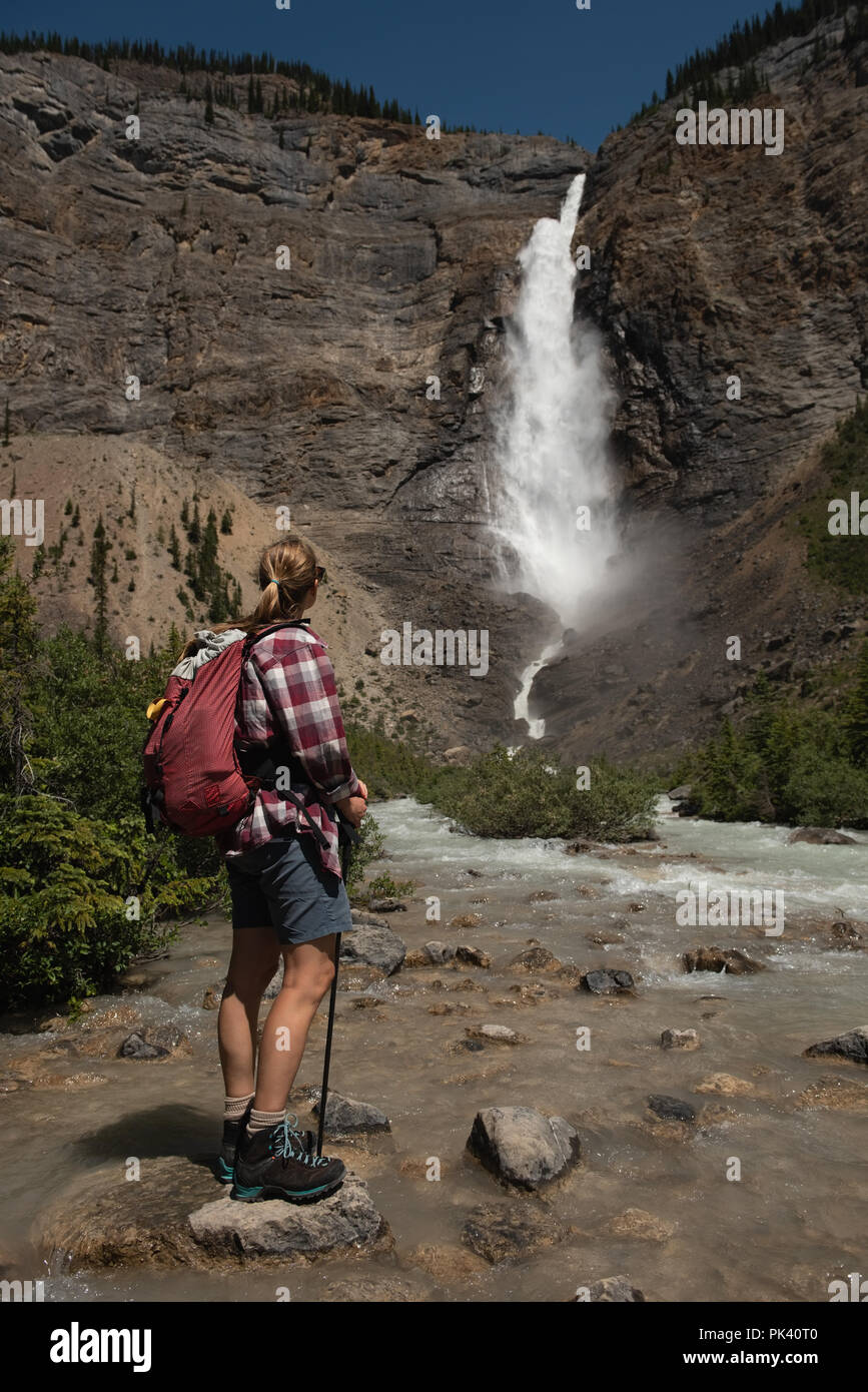 Escursionista femmina guardando a cascata Foto Stock