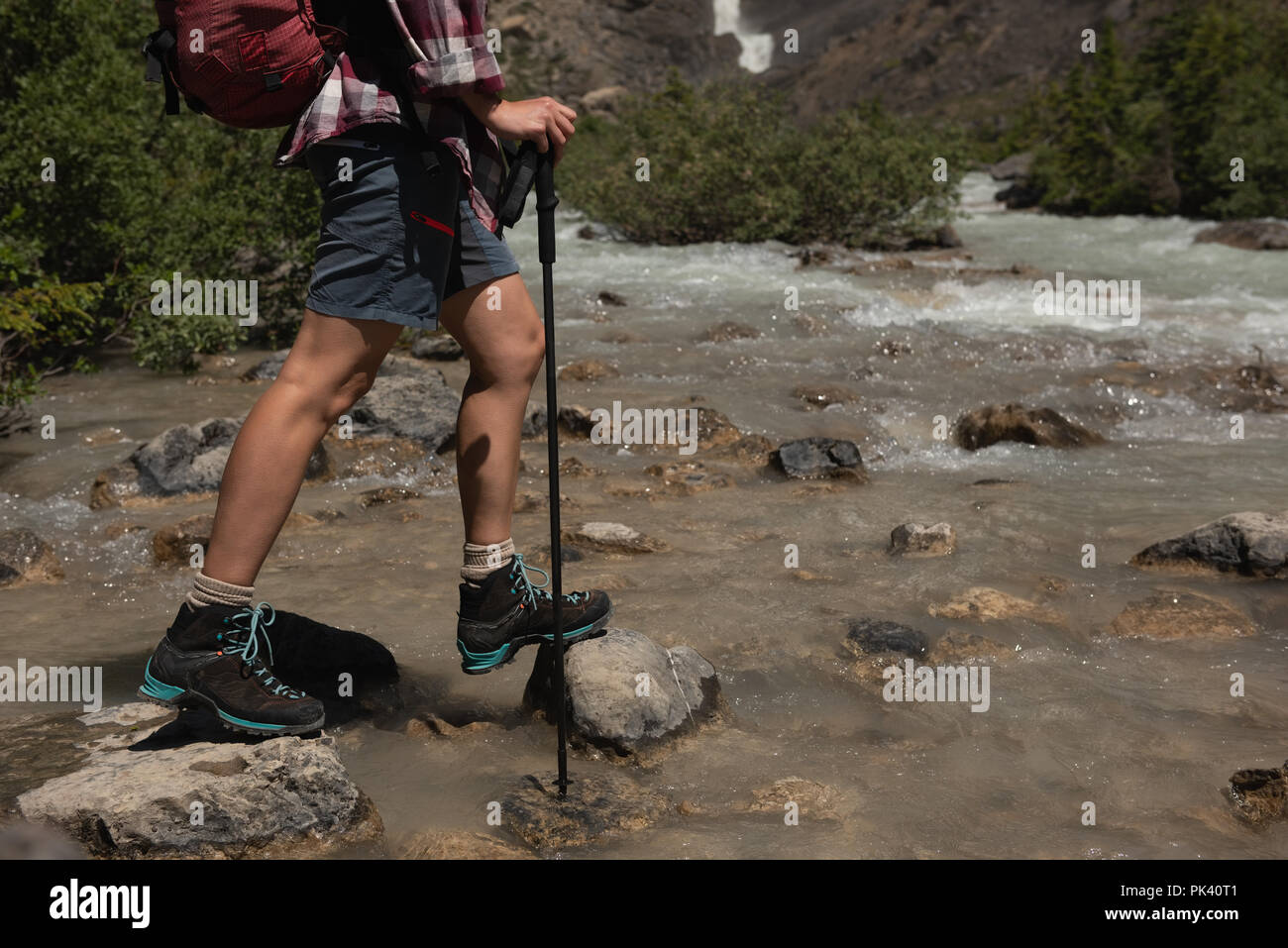 Escursionista femmina che attraversa il torrente a campagna Foto Stock