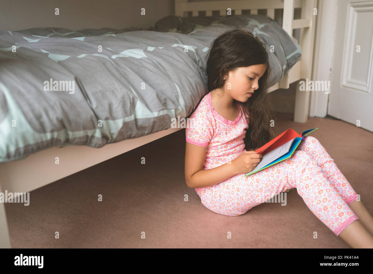 Lettura della ragazza prenota in camera da letto Foto Stock