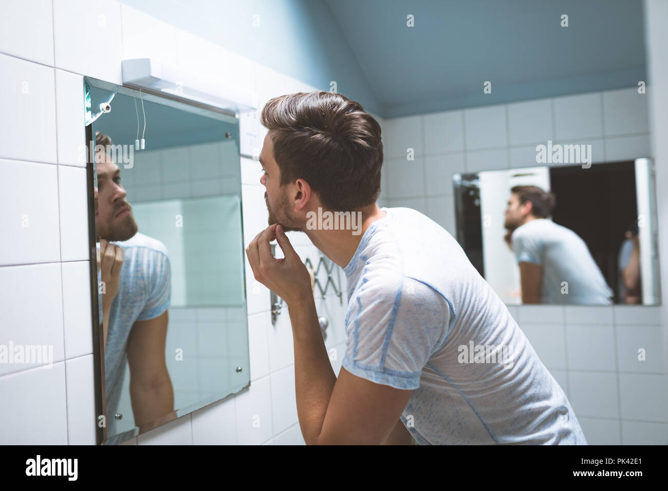 Uomo che guarda nello specchio a casa Foto Stock